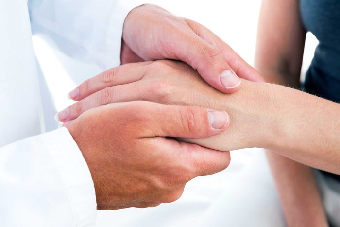 doctor's hands holding a patient's hand