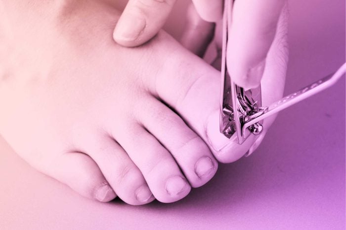 person using nail clippers on big toe