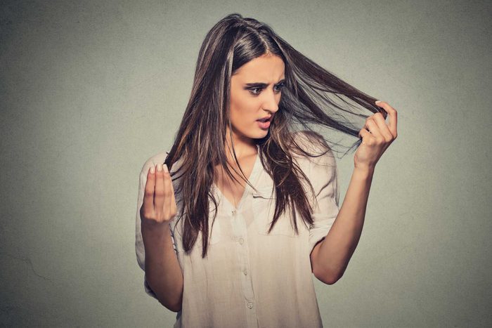woman looking at her hair in alarm