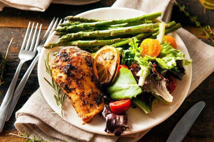 Dinner plate with chicken, asparagus and salad.