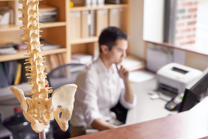 close up of human spine with man in background