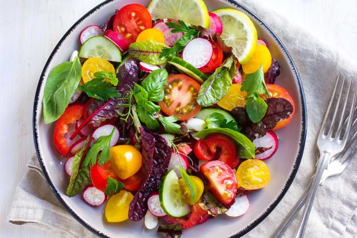 salad with tomatoes, leafy greens, radishes, and lemon slices