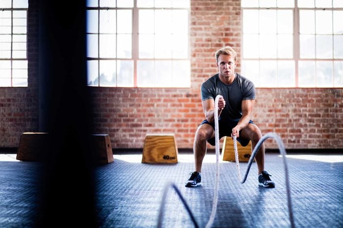 young man working out with ropes in a gym