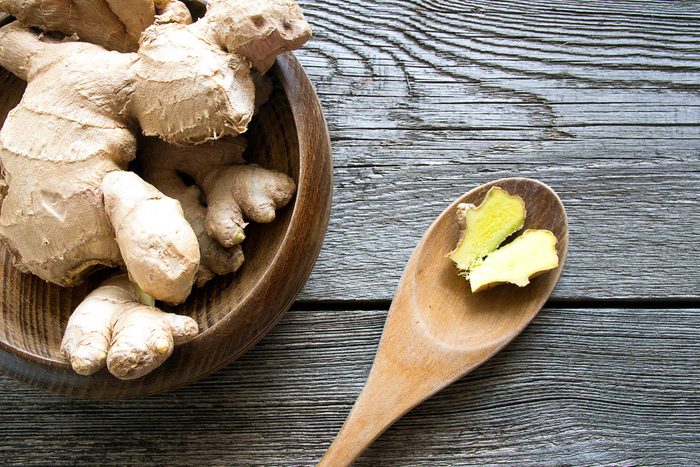 A bowl of fresh ginger root and a spoon with a split piece of ginger.