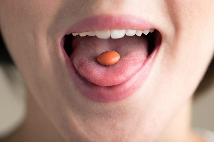 closeup of a pill on a woman's tongue