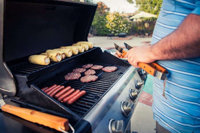 man grilling meat and corn