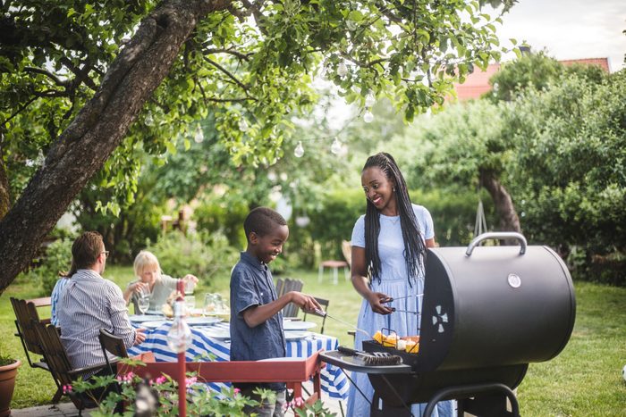 mother and son grilling food for barbecue with family