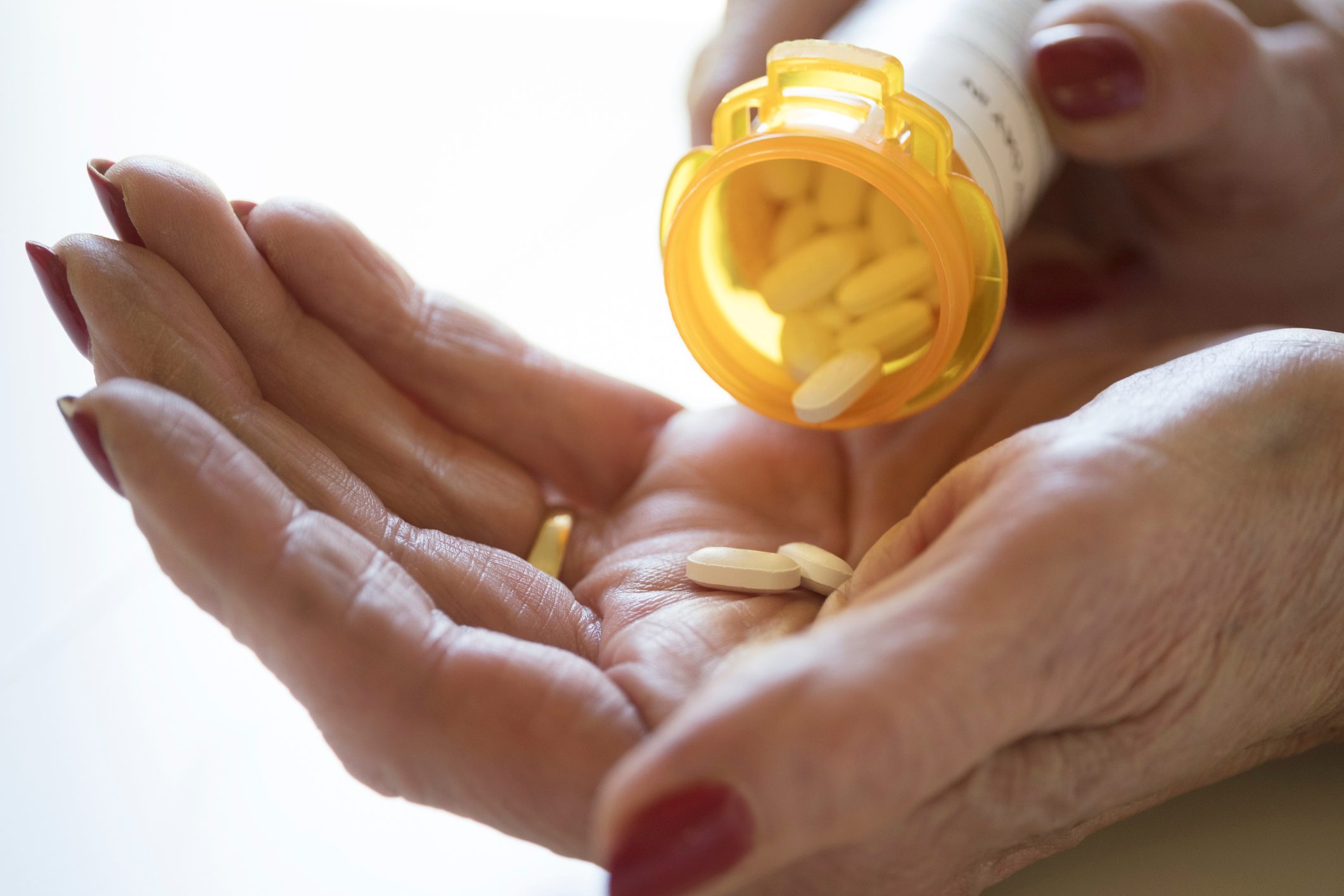 close up of woman pouring pills into hand