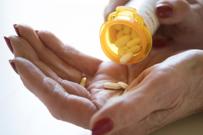 close up of woman pouring pills into hand