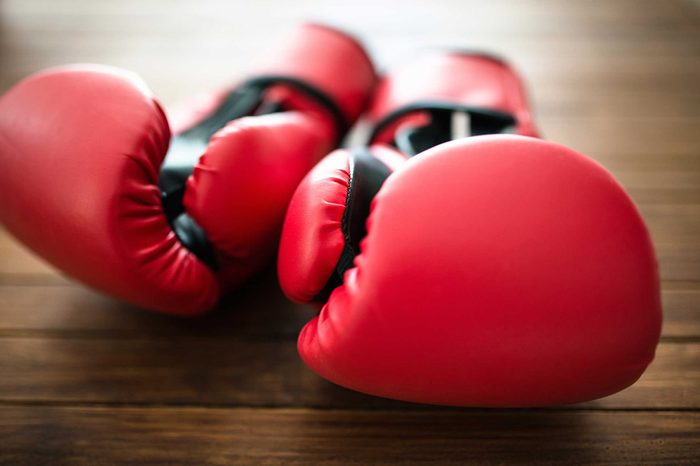 Pair of red boxing gloves on a wooden surface.