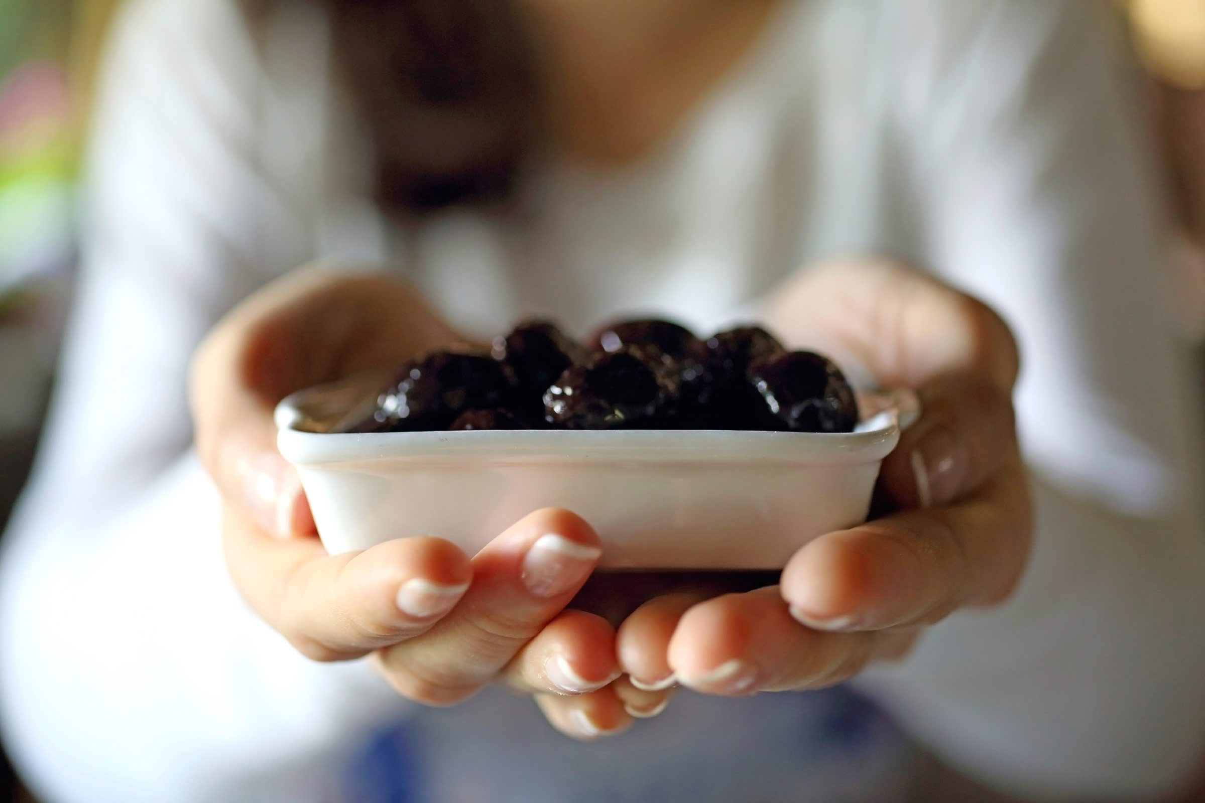 woman holding dish of dark olives
