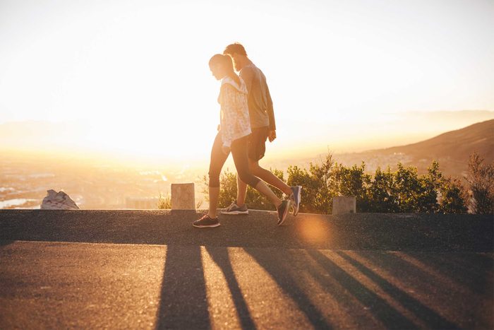 man and woman walking at sunset