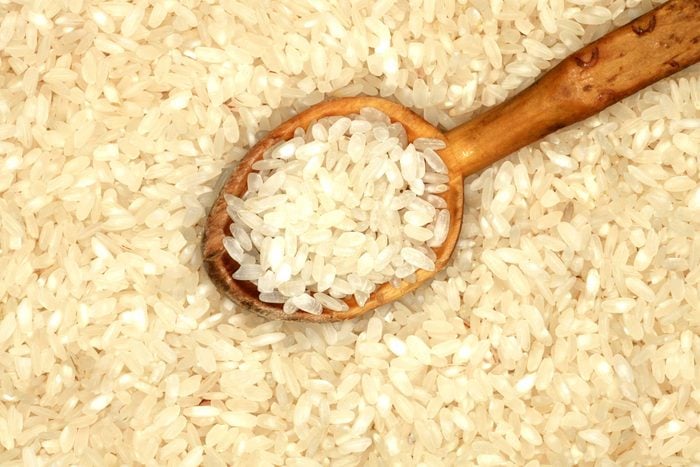 dried white rice grains with a wooden spoon