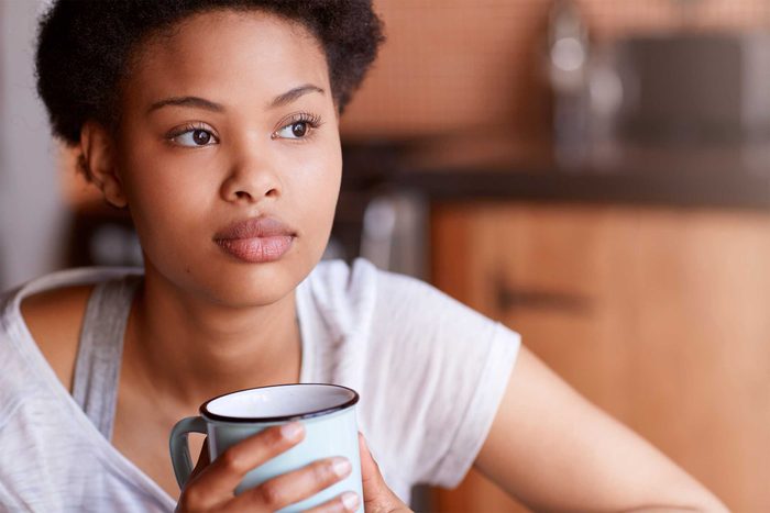 Black woman holding a mug and staring thoughtfully