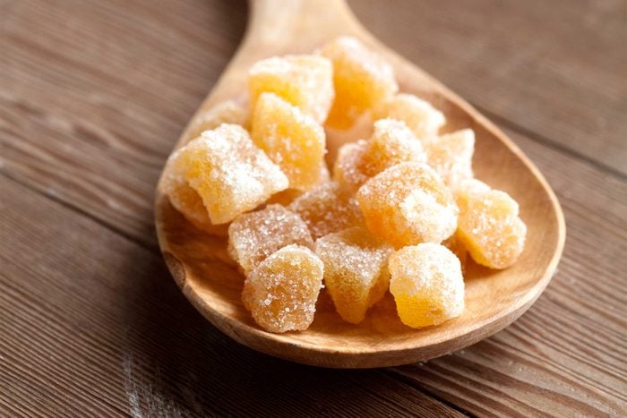 candied ginger cubes on a wooden spoon