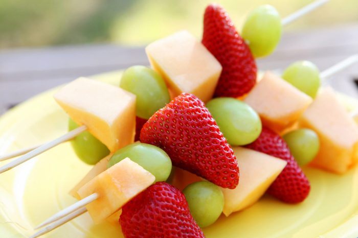 Fruit kabobs wit strawberries, cantaloupe, and grapes.