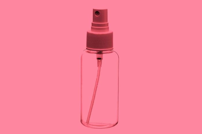 Clear bottle of rosewater on a pink background.