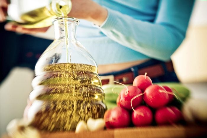 person pouring olive oil in decanter