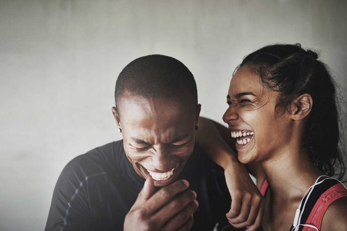 Couple wearing workout gear smiling and laughing.
