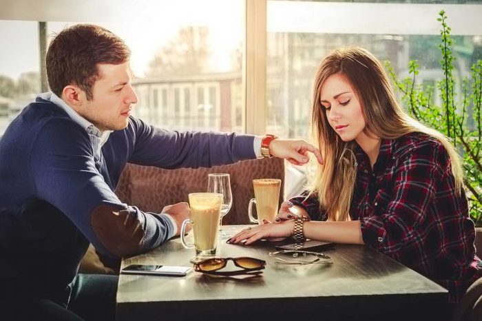 Man and woman sitting at a restaurant table talking.