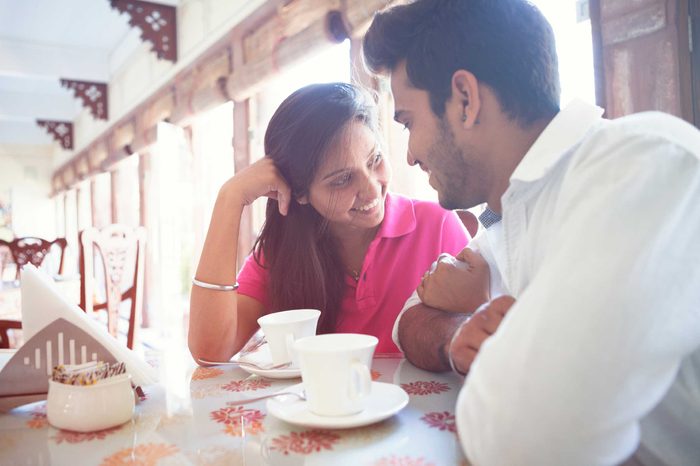A man and woman sitting in a cafe talking and smiling.