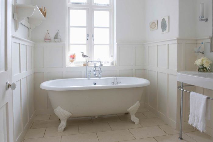 white clawfoot tub in a white sunny bathroom
