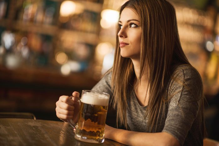 Woman in bar drinking beer alone
