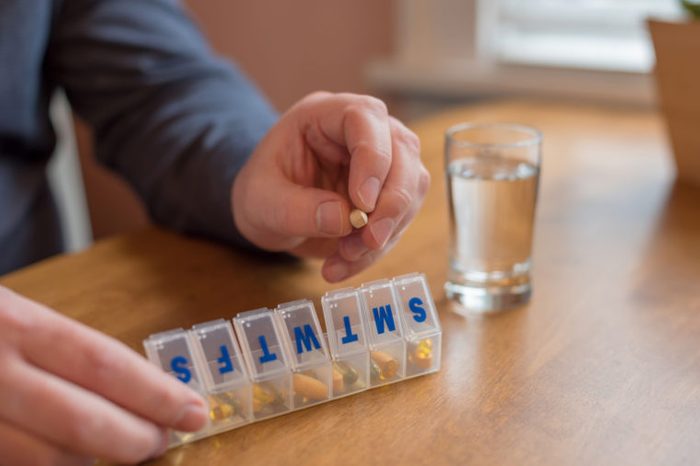 man taking pill out of weekly pill box