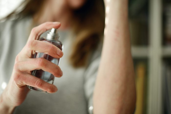 close up of woman spraying perfume on arm