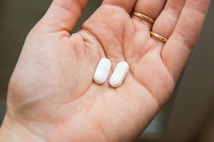 hand holding two white pills