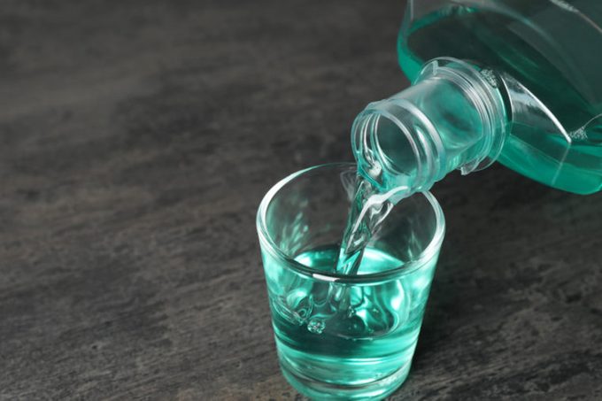 Pouring mouthwash in glass and space for text on dark background. Teeth care