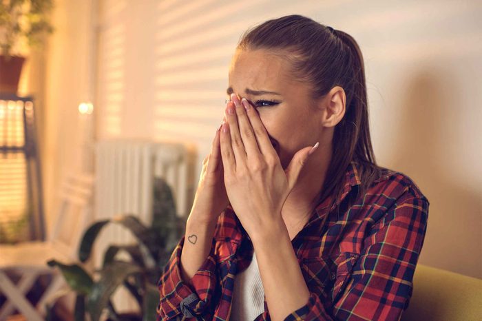 Woman in a plaid shirt covering her mouth with her hands as if crying.