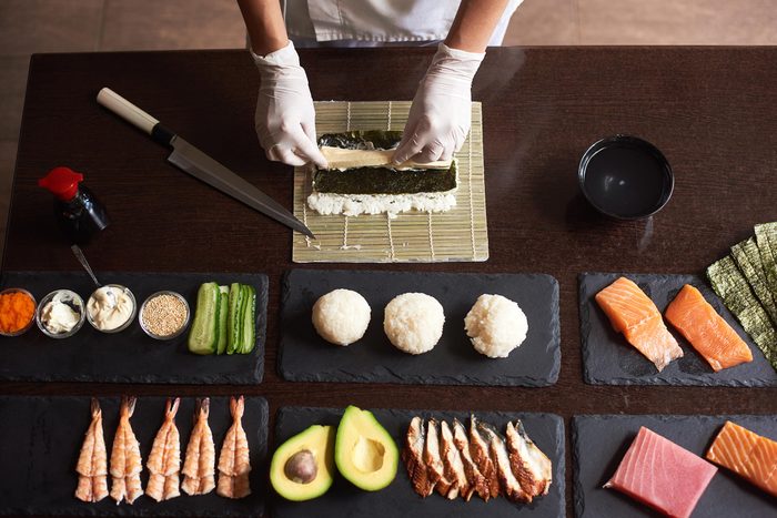 Sushi chef making sushi rolls.