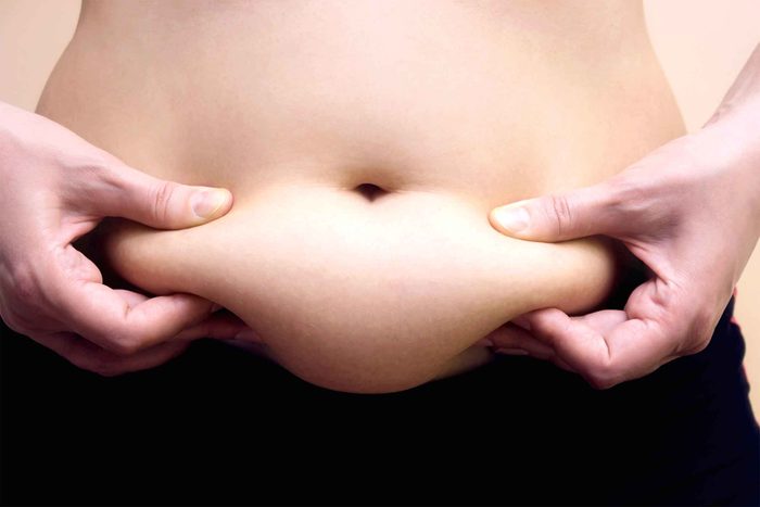 woman pinching her bulging bare belly