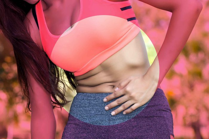 woman in sports bra holding her stomach