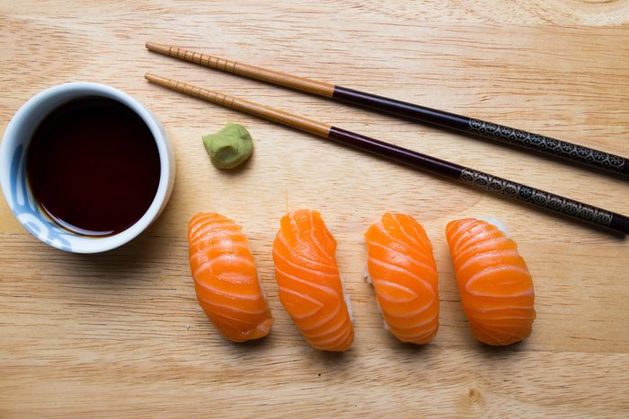 Four pieces of salmon sashimi and soy sauce.