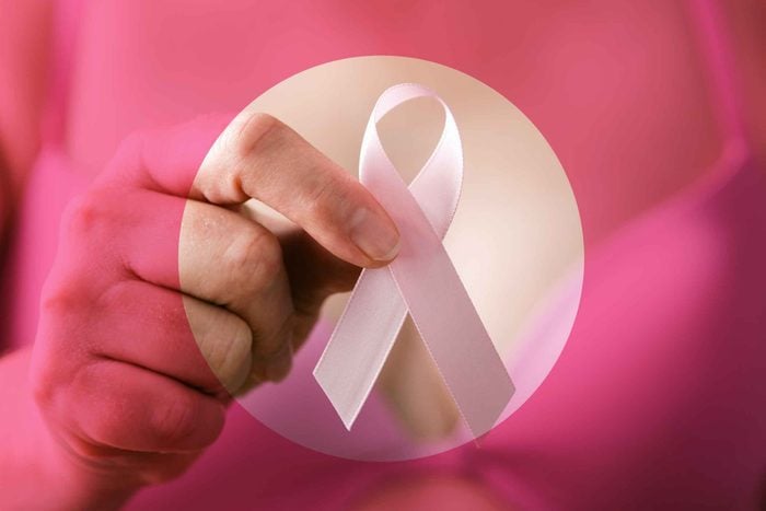 closeup of a hand holding a pink breast cancer ribbon