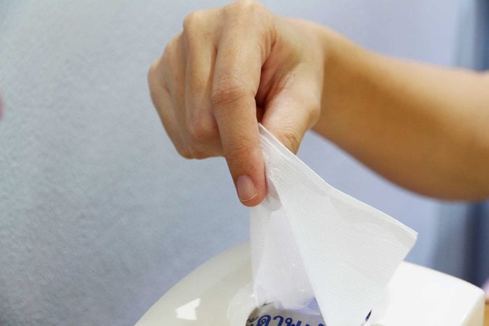 Person pulling a tissue out of a tissue box.