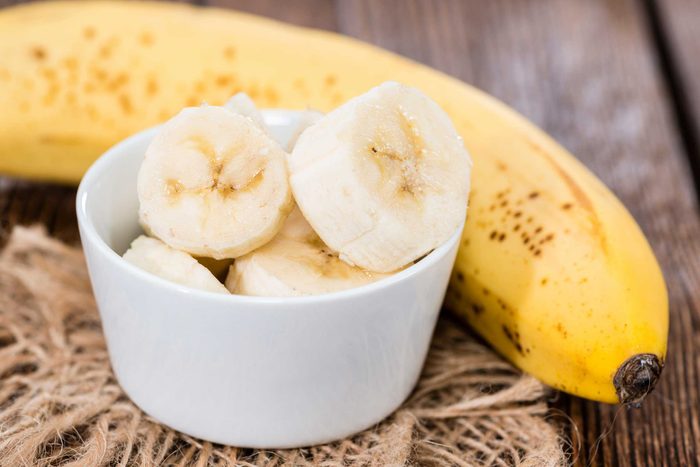 bowl with banana slices in front of ripe banana