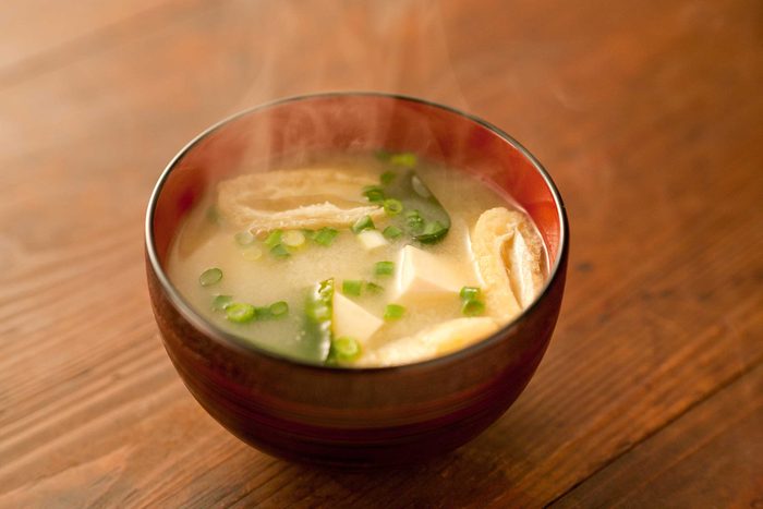 bowl of steaming miso soup with green onion and tofu