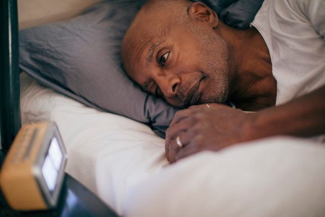 man laying awake in bed at night unable to sleep