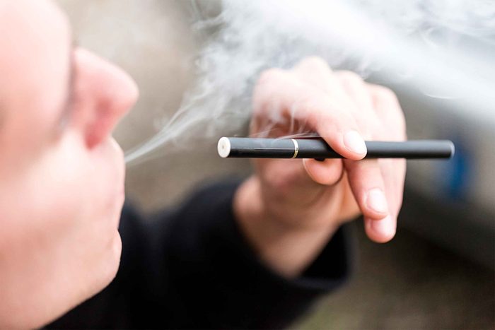 person exhaling vapor from e-cigarette