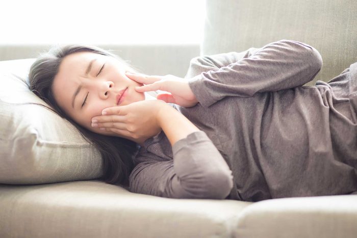 woman in pain lying down and holding her jaw