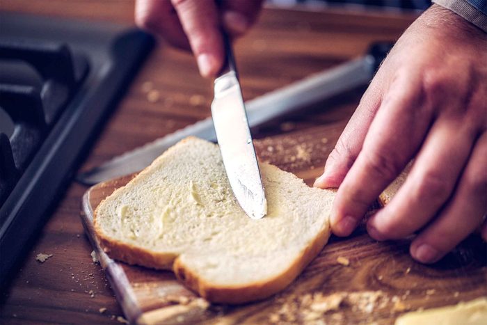 Hand spreading butter on toast