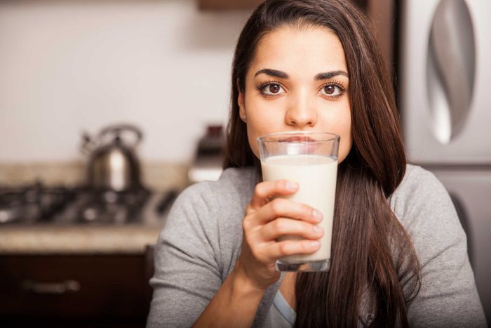 brunette woman with brown eyes holding a glass of milk