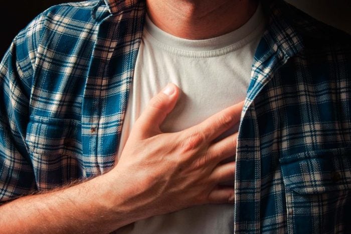 Man holding his heart as if having chest pain.