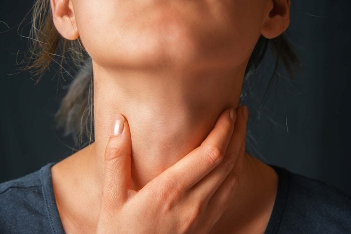Woman feeling her throat with her hand.