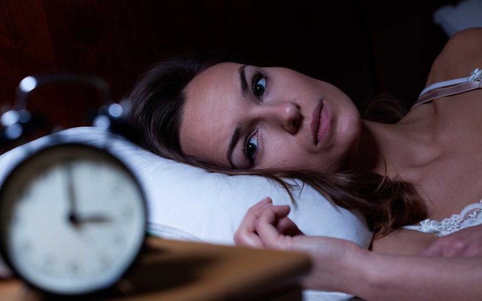 Woman looking at clock in bed