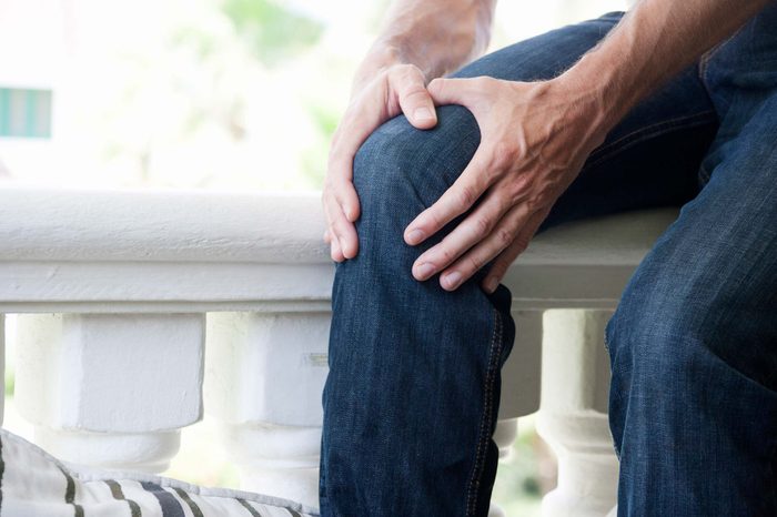 Man in jeans holding his knee.