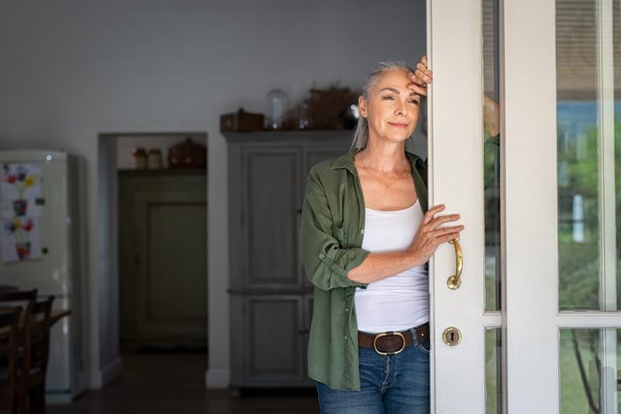 woman standing at home entrance looking outside